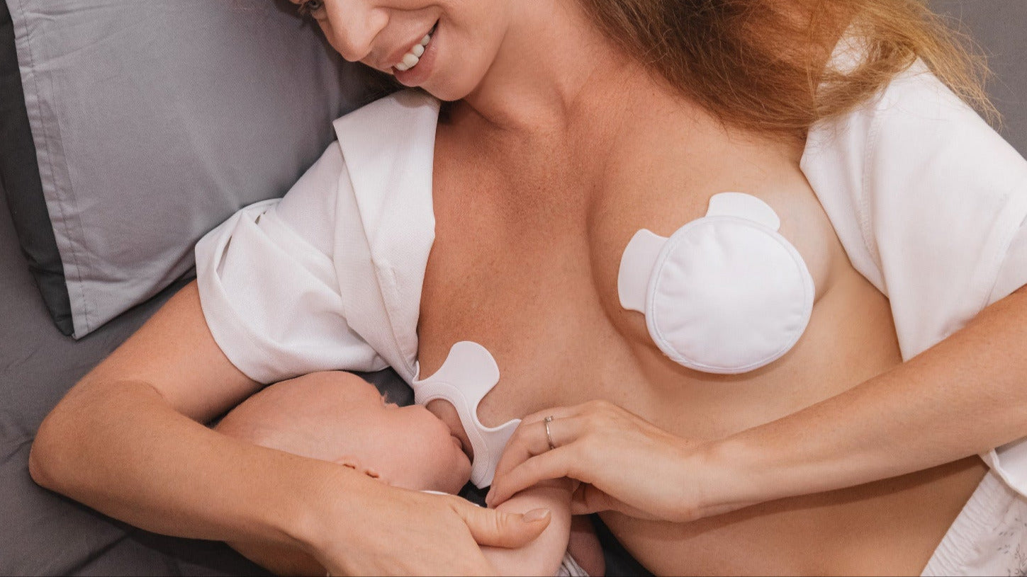 Glückliche Mutter im Bett mit NuNi Pads die ihr Kind stillt